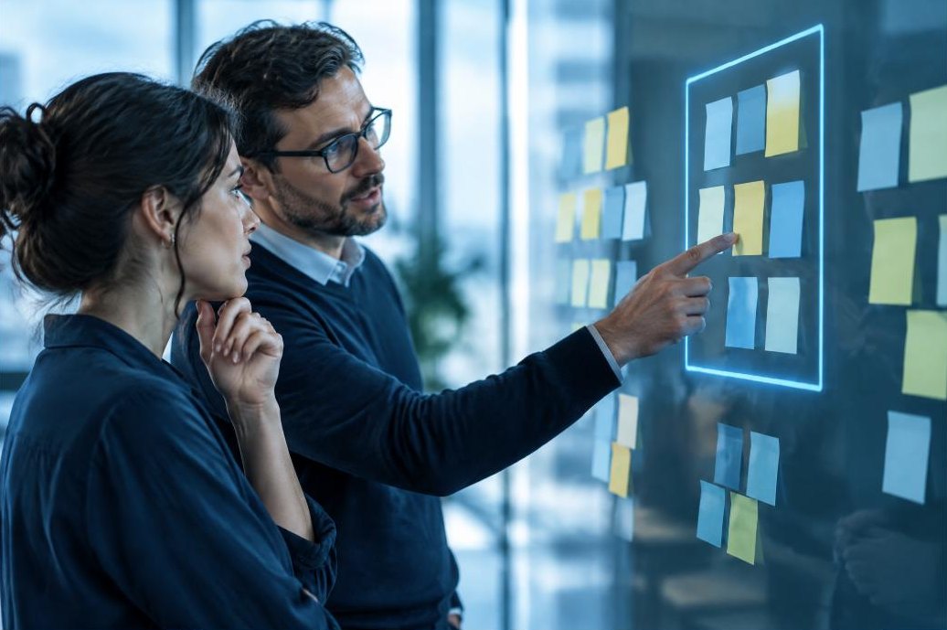 Two people defining a project scope on a glass wall